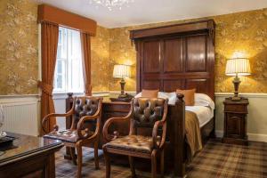 a bedroom with a bed and a desk and chairs at Tweeddale Arms Hotel in Gifford