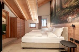 a bedroom with a white bed and a painting on the wall at Casa Pencio in Pozza di Fassa +57 photos