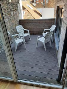 three white chairs sitting on a deck with a building at apartment Amsterdamstr 1st fl in Ostend