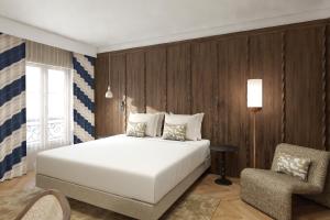 a bedroom with a white bed and a chair at Hôtel de l'Europe by HappyCulture in Strasbourg
