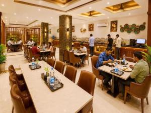 a group of people sitting at tables in a restaurant at Hotel Airport Hilton Sky IGI Delhi Airport Terminal 3 With- Free Airport Pickup in New Delhi