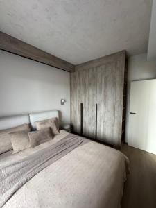 a bedroom with a large bed with a wooden wall at Locusdo apartment Nr 27 in Vilnius