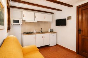 a kitchen with white cabinets and a yellow couch at Refugio La Presa in Chulilla