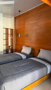 two beds in a room with wooden walls at The Tree Poolbar&Resort in Gili Islands