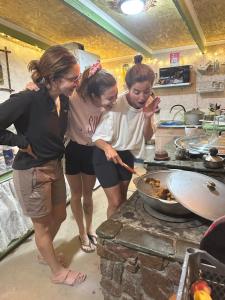 three women standing in a kitchen preparing food in a pan at JAPAR guest house in Bokonbayevo