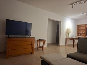 a living room with a flat screen tv on a dresser at Apres-midi in Dawwār Abū Maḩrūs