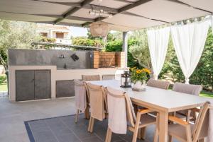 an outdoor dining area with a white table and chairs at Ocean Private Villas - Pefkochori Halkidiki in Pefkochori