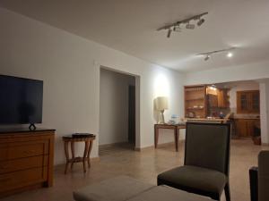 a living room with a flat screen tv and a chair at Apres-midi in Dawwār Abū Maḩrūs