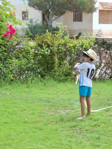 a young boy standing in a yard holding a bat at Apres-midi in Dawwār Abū Maḩrūs