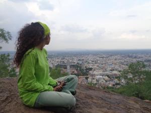 a girl sitting on a rock looking at a city at Urban Hostels in Tiruvannāmalai
