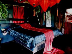 a bed with a red blanket on top of it at Le Nid Du Dragon Rouge in Courniou