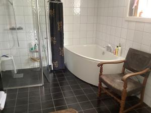 a bathroom with a tub and a chair and a shower at Fagertun in Lillesand