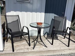 a glass table and two chairs on a patio at Fagertun in Lillesand