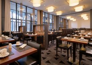 a restaurant with wooden tables and chairs and windows at Sheraton Berlin Grand Hotel Esplanade in Berlin