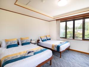two beds in a room with a window at Beni Fujien in Yamanakako