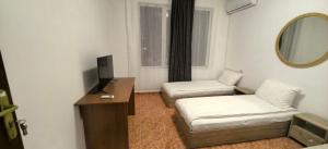 a room with two beds and a desk and a mirror at Стаи за гости Ескейп in Isperikh