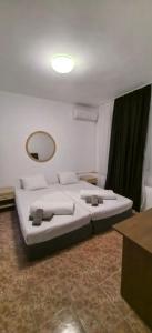 a bedroom with a large white bed with a mirror at Стаи за гости Ескейп in Isperikh
