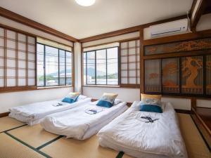 three beds in a room with windows at Beni Fujien in Yamanakako