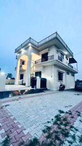 a white house with a driveway in front of it at Mannat Villa Homestay in Rāmnagar