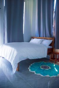 a bedroom with a white bed with a blue curtain at Wete View Hotel in Wete