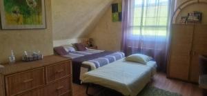 a bedroom with two beds and a dresser and a window at Chambre d'Hotes Le Vogelgarten in Sigolsheim