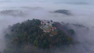 an aerial view of a house on a hill in the fog at Mountain Vista Resort in Kalpetta