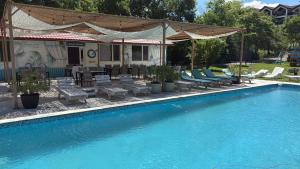 a swimming pool with chairs and umbrellas next to a house at Casa Știuca Șchioapă in Băltenii de Sus