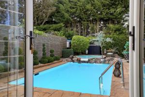 a swimming pool seen through a sliding glass door at The Luxe Pool House, Westoning in Westoning