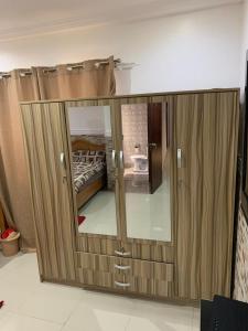 a large wooden cabinet with a mirror in a room at FREDJACKSAIR BNb in Koforidua
