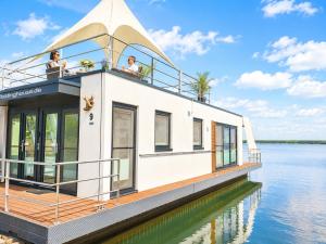 a houseboat on the water with people on the deck at Floatinghouse Milan - LP9 in Vetschau