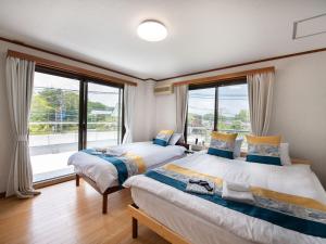 two beds in a room with large windows at Beni Fujien in Yamanakako +58 photos