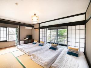 three beds in a room with large windows at Beni Fujien in Yamanakako