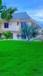 a large house with two palm trees in front of it at ANITHA EXECUTIVe LODGE in Kibaha