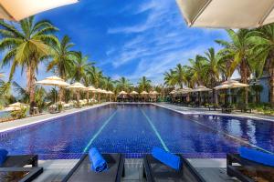 a swimming pool with palm trees and umbrellas at Amarin Resort & Spa Phu Quoc in Phu Quoc