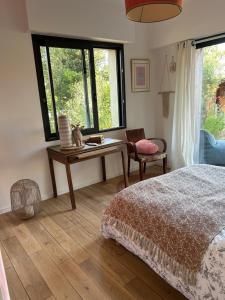 a bedroom with a bed and a table and windows at Les mimosas in Tosse
