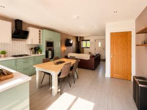a kitchen and living room with a wooden table in a room at Hawthorn Cottage in Tenby