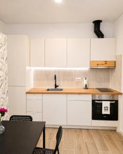 a kitchen with white cabinets and a sink and a table at Casa Nº9 - Vila d'Óbidos in Óbidos
