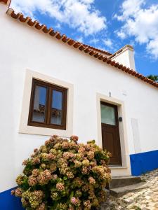 a white house with a flowering bush in front of it at Casa Nº9 - Vila d'Óbidos in Óbidos