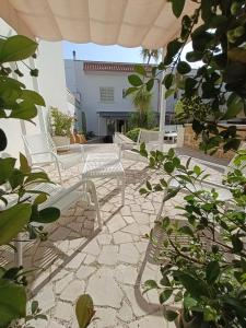 a patio with white chairs and an umbrella at Vianova Affittacamere in Giurdignano