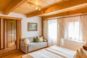 a bedroom with a bed and a couch and a window at Schmiedlehnerhof in Birnberg
