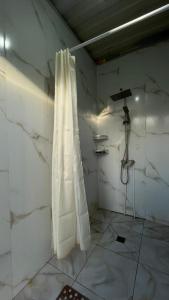 a bathroom with a shower and a white marble wall at Karakol Yurt Village in Karakol