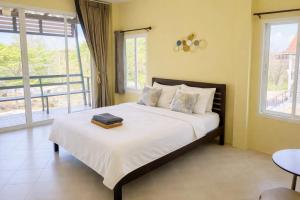a bedroom with a bed with white sheets and windows at Koniix Garden Cottage Ko Sichang in Ko Si Chang