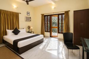 a bedroom with a bed and a chair and a window at Next Generation Guest House in kolkata