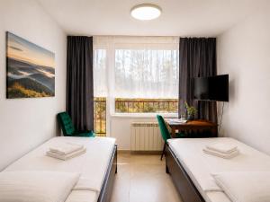 a room with two beds and a desk and a window at Dom Wczasowy GLOBUS in Ustroń