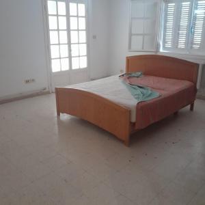 a wooden bed in a room with two windows at Rejiche in Rejiche