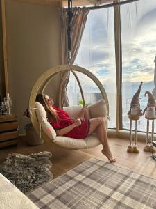 a woman sitting on a swing in a living room at ZakoGlamp Glamping Pod Gubałówką z Jacuzzi in Ząb