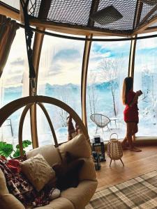 a woman standing in a room with a large window at ZakoGlamp Glamping Pod Gubałówką z Jacuzzi in Ząb +71 photos