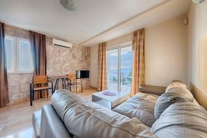 a living room with a couch and a large window at ZIS LUX Apartments Pool in Utjeha