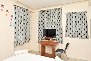 a room with a tv and a desk with a chair at Hotel Ganesh Mahalakshmi Inn in Guntūr