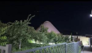 a building at night with a fence and trees at Bars guest House in Barskoon